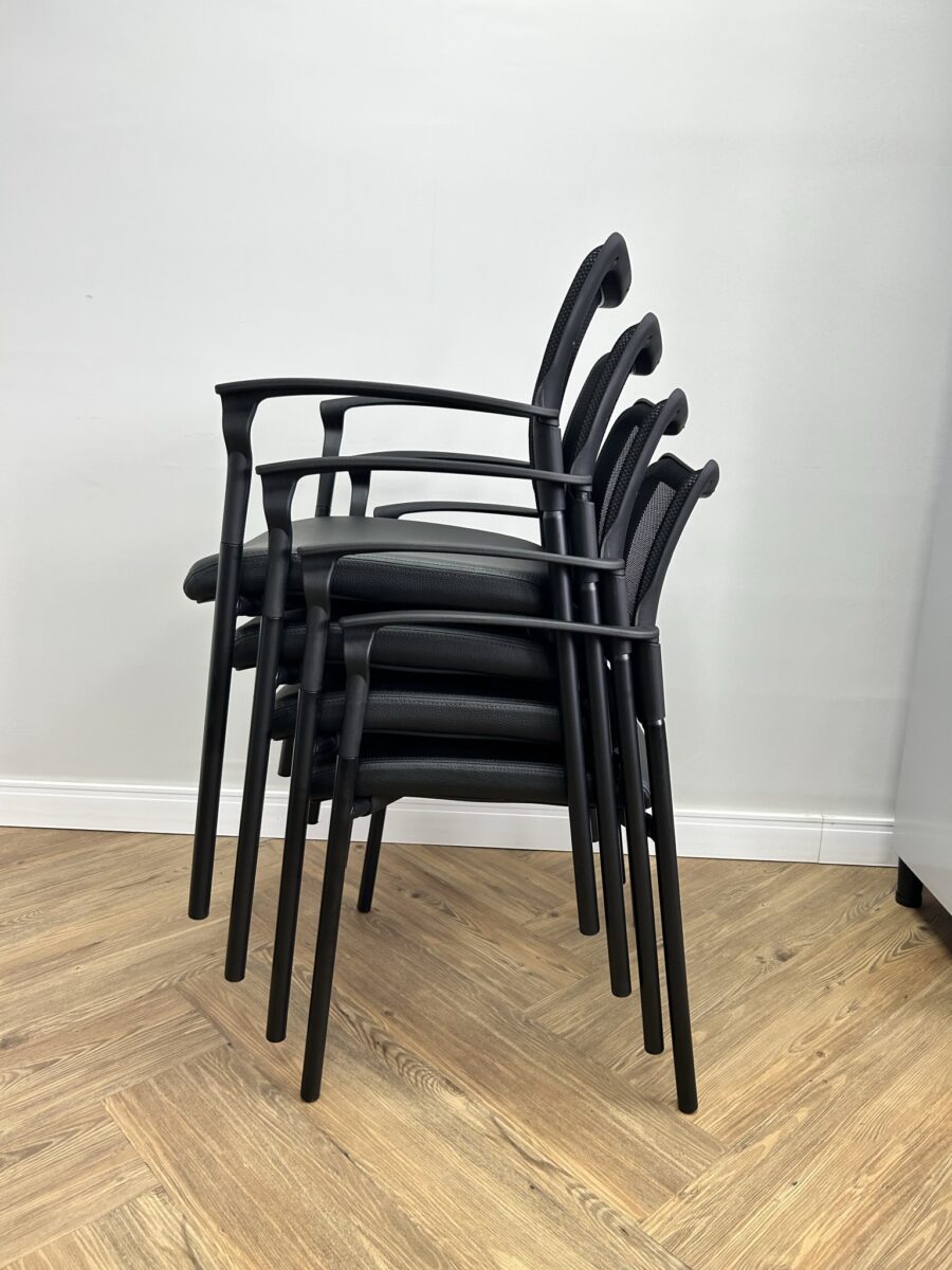 Visão detalhada do empilhamento de quatro unidades da Cadeira Fixa Empilhável com Tela para Sala de Treinamento (modelo Force Duratta). Cadeiras pretas com assento estofado em couro sintético e encosto mesh, otimizando espaço em ambientes corporativos e auditórios.